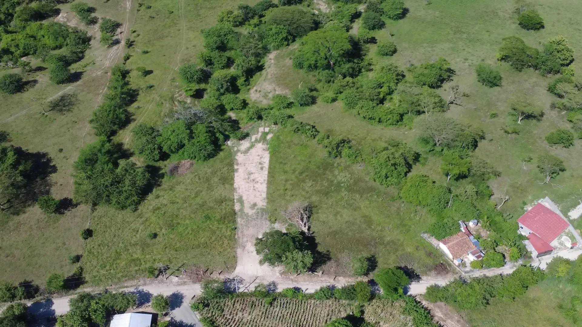 Vista aérea del proyecto Amayo (El Copinolito) en Tejutla, Chalatenango, con terrenos verdes, acceso de tierra y vegetación natural